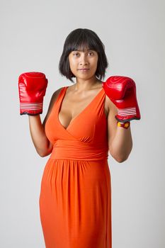 Young sexy philipino woman, wearing a low cut orange dress, with boxing glove up