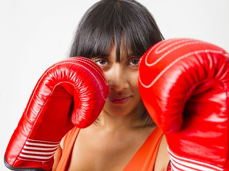 Young asian woman protecting her face with red boxing glove