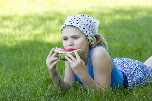 cute little girl eating watermelon on the grass