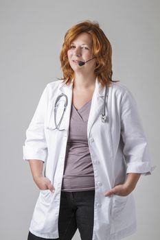 forty something woman doctor with red hair with a stethoscope and a headset