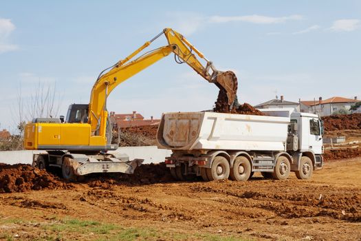 industrial excavator loading tipper truck on construction site