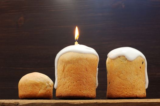 Kulichi, traditional Russian Easter cake with icing and candle on wooden background horizontal