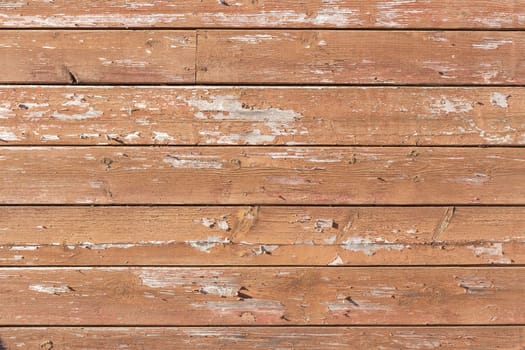 Texture of red paint peeling off boards 