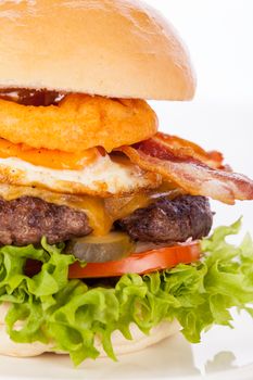 Delicious egg and bacon cheeseburger with a nutritional filling of salad ingredients, a ground beef patty, cheese, fried egg and crispy bacon on a white crusty roll