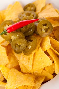 Bowl of crisp golden corn nachos with cheese sauce or dip and olives served as a starter or appetizer to a meal