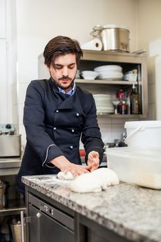 Professional cook or chef in a commercial kitchen tossing dough while making pastries for desserts in a restaurant or hotel