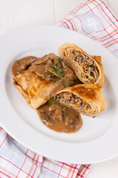 Savory mince pancakes or tortillas cut open to show the ground or minced meat and vegetable filling in a rich tasty gravy