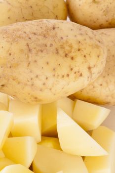 Three Whole Potatoes and Chopped Peeled Pieces on Cutting Board