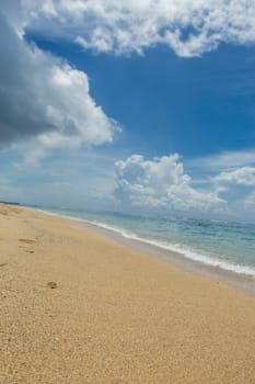 Beautiful tropical beach with lush vegetation fringing golden sand and a tranquil ocean with gentle surf breaking on the beach