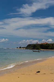 Beautiful tropical beach with lush vegetation fringing golden sand and a tranquil ocean with gentle surf breaking on the beach