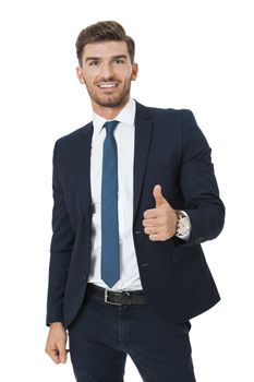 Stylish successful handsome young businessman standing in a relaxed pose with his hands in his pockets and his suit jacket open, isolated on white