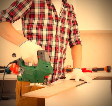 repairman with jigsaw shortens the floorboard