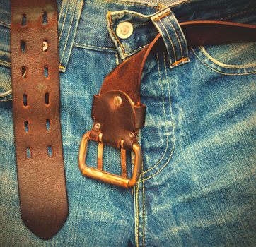 aged blue jeans with unfastened old leather belt