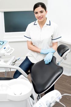 Female dental assistant standing beside chair