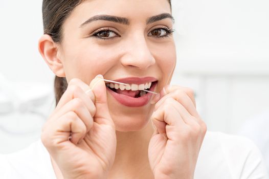 Young woman using dental floss in her mouth