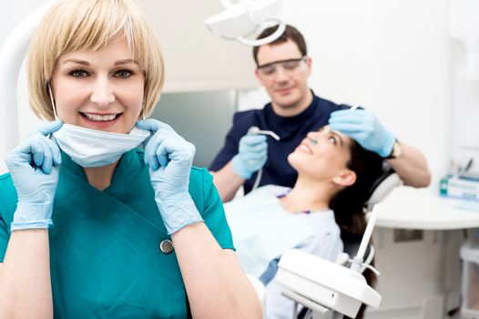 Female dental assistant removing her face mask 