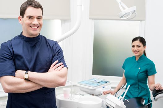 Male dentist with his assistant behind at dental clinic