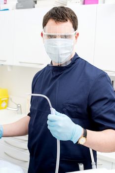 Male dentist posing with dental cleaning tools