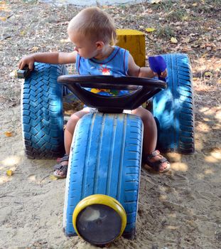 oy playing toy in the playground with a machine with car tires