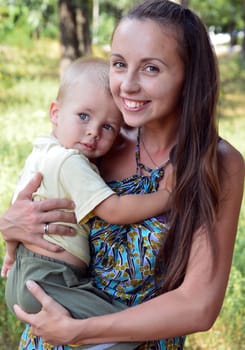 mother holding baby son in her arms on a greenish background