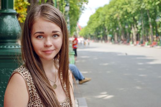 Portrait of a young girl on the background of the avenue theme park