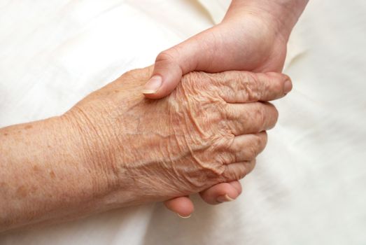 the hands of her grandmother and granddaughter on a light background