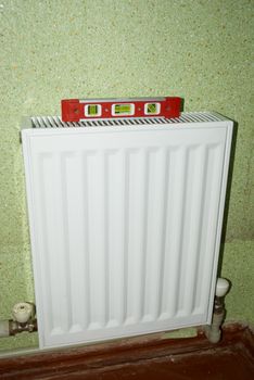 radiator with a red background at the level of green wallpaper