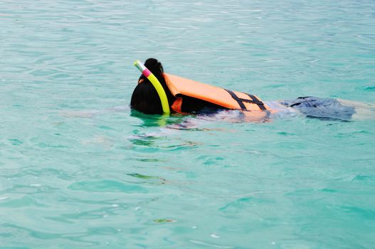 Girl swimming in life jacket with mask and breathing tube