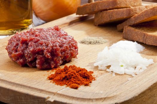 Steak tartar with the fried bread on the wooden trencher