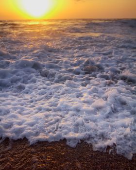 Gentle warm sea on backdrop of enchanting sunset. Foamy surf. Mediterranean sea.