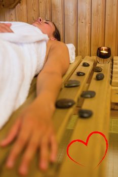 Calm brunette woman lying in a sauna against heart