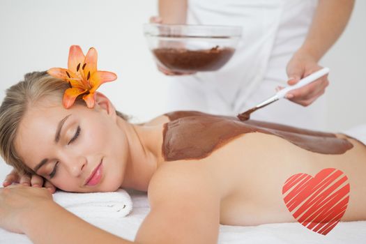 Beautiful blonde enjoying a chocolate beauty treatment  against red heart