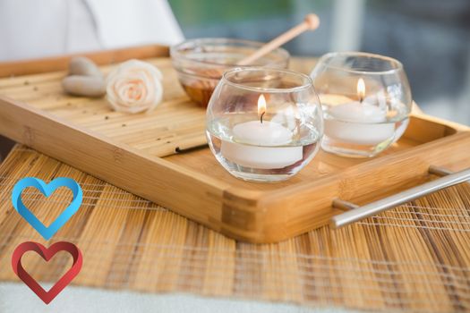 Candles and beauty treatment on tray against hearts