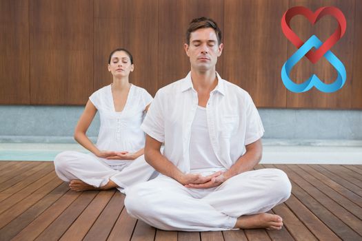 Peaceful couple in white sitting in lotus pose together against linking hearts