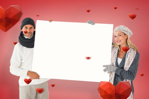 Smiling couple in winter fashion holding poster against red vignette