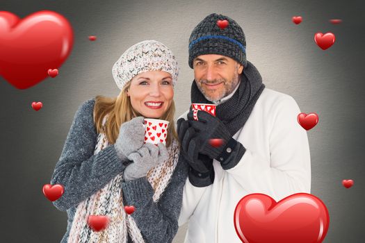 Happy couple in winter fashion holding mugs against white background with vignette