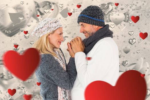 Couple in winter fashion embracing against grey valentines heart pattern