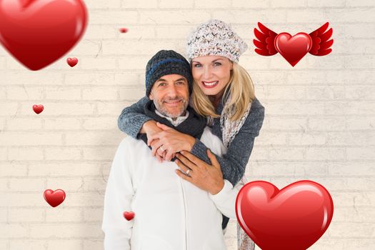Happy couple in winter fashion embracing against white wall