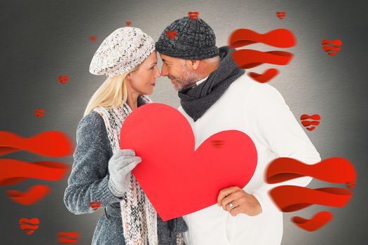Smiling couple in winter fashion posing with heart shape against white background with vignette