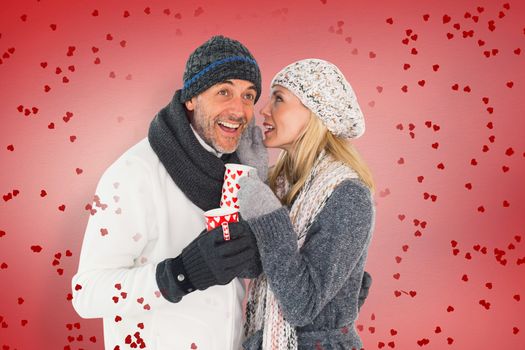 Happy couple in winter fashion holding mugs against red vignette