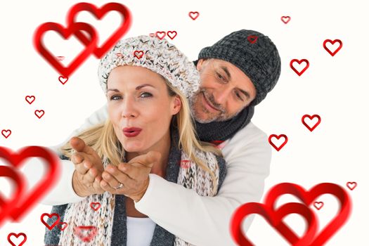 Smiling couple in winter fashion posing against hearts