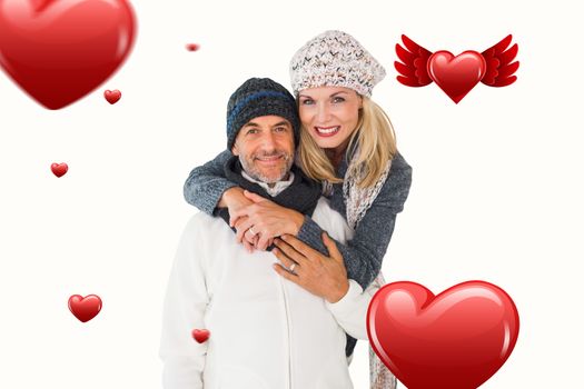 Happy couple in winter fashion embracing against hearts