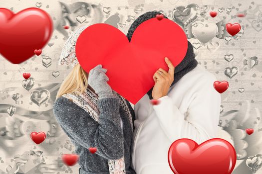 Couple in winter fashion posing with heart shape against grey valentines heart pattern