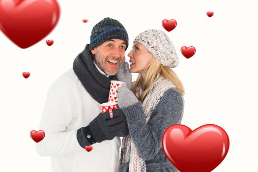 Happy couple in winter fashion holding mugs against hearts