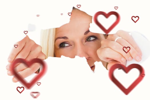 Blonde woman looking through torn paper against hearts