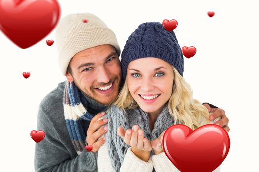 Attractive couple in winter fashion smiling at camera against hearts