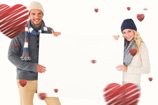 Attractive couple in winter fashion showing poster against hearts
