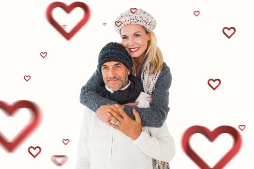 Happy couple in winter fashion embracing against hearts