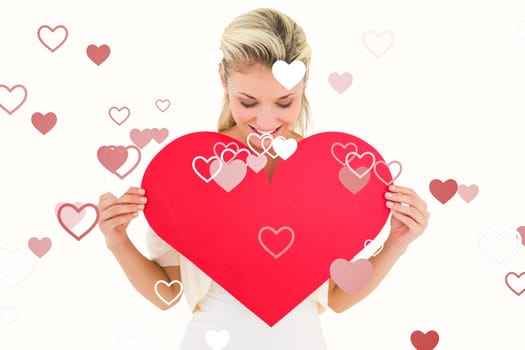 Attractive young blonde showing red heart against valentines heart design