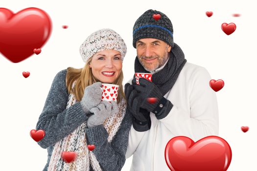 Happy couple in winter fashion holding mugs against hearts